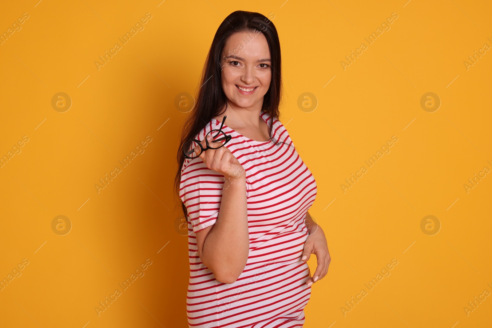 Photo of Beautiful overweight woman with charming smile on yellow background