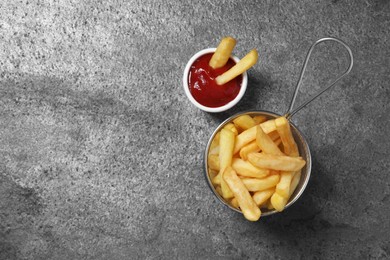 Photo of Tasty french fries and ketchup on grey table, flat lay. Space for text