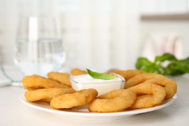 Photo of Delicious onion rings with sauce on white wooden table, closeup