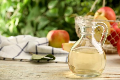 Photo of Natural apple vinegar and fresh fruits on white wooden table. Space for text