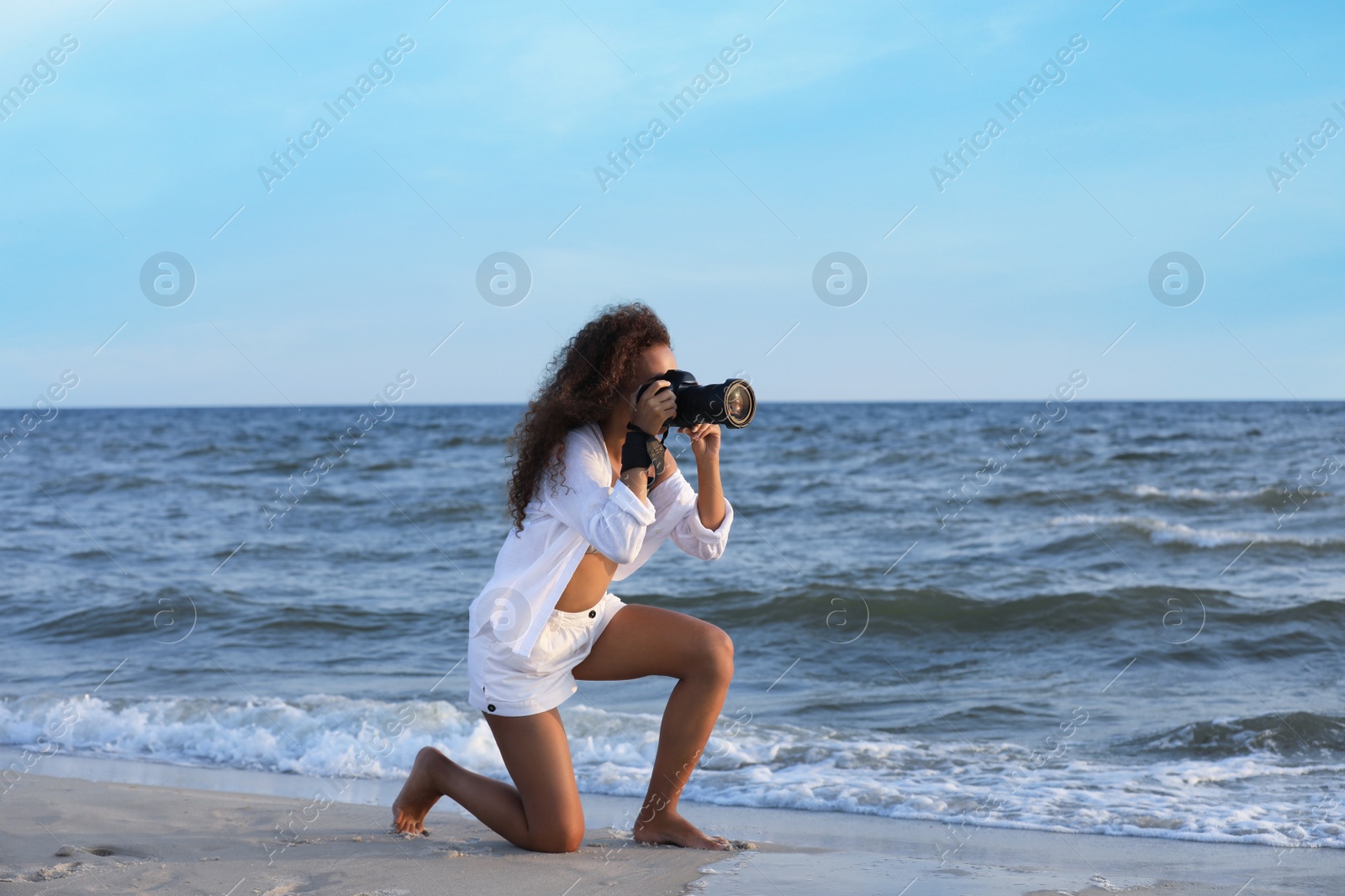 Photo of African American photographer taking photo with professional camera near sea
