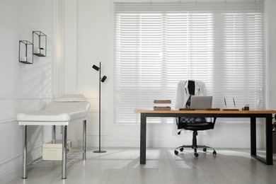 Photo of Modern medical office interior with doctor's workplace and examination table