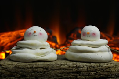 Photo of Cute decorative snowmen on wooden surface near fireplace