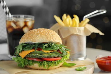 Photo of Tasty vegetarian burger served with french fries and soda drink on white table, closeup. Space for text