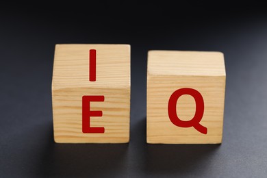 Photo of Wooden cubes with letters E, I and Q on black background