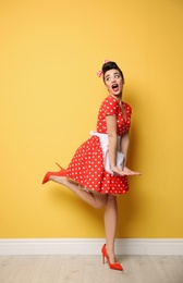 Portrait of funny young housewife against color wall