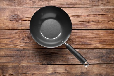 Empty iron wok on wooden table, top view. Chinese cookware