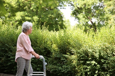 Photo of Elderly woman with walking frame outdoors. Medical help