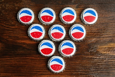 Photo of MYKOLAIV, UKRAINE - FEBRUARY 11, 2021: Pepsi lids on wooden background, flat lay