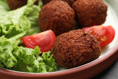 Photo of Delicious falafel balls, tomatoes and lettuce on plate, closeup. Vegan meat products