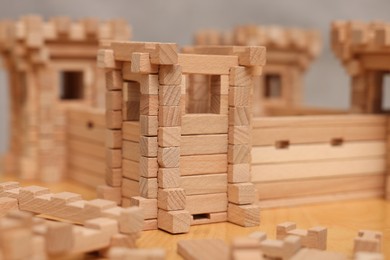 Photo of Wooden fortress and building blocks on table, closeup. Children's toy