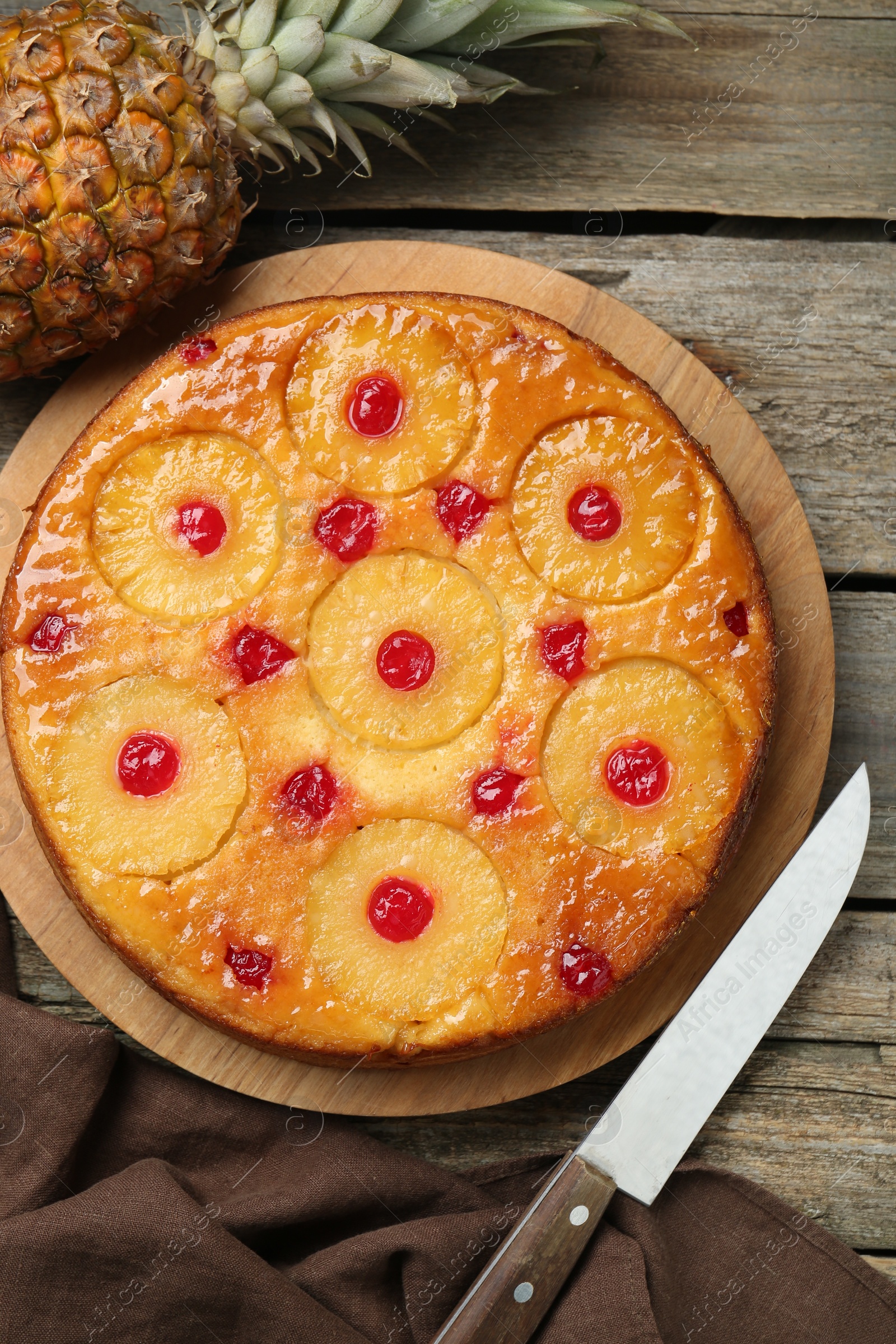 Photo of Tasty pineapple cake with cherries on wooden table, flat lay