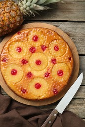 Tasty pineapple cake with cherries on wooden table, flat lay