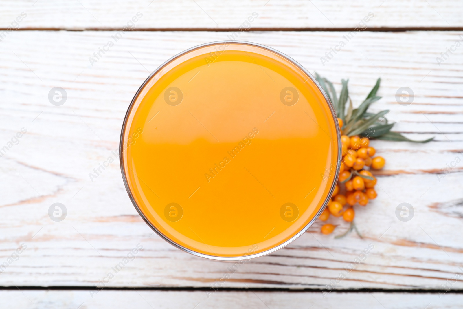 Photo of Delicious sea buckthorn juice and fresh berries on white wooden table, top view