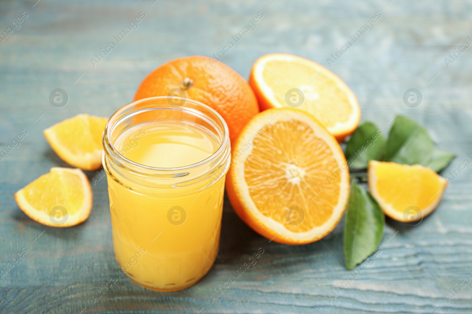 Photo of Delicious orange juice and fresh fruits on light blue wooden table