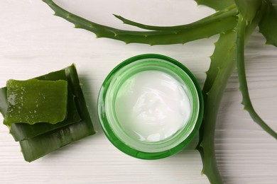 Jar of cosmetic gel and aloe vera leaves on white wooden table, flat lay