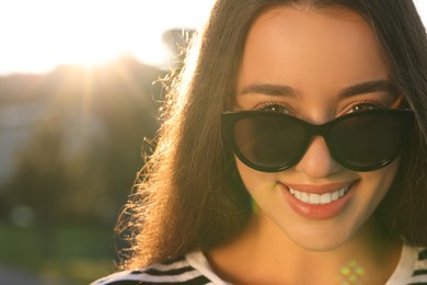 Photo of Beautiful smiling woman in sunglasses outdoors, space for text