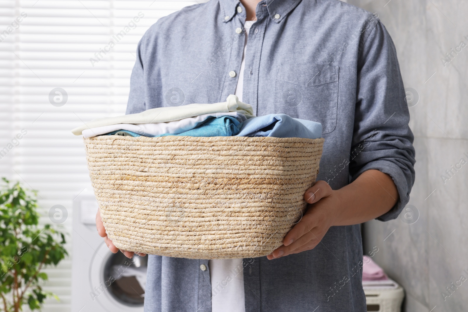 Photo of Man with basket full of laundry in bathroom, closeup