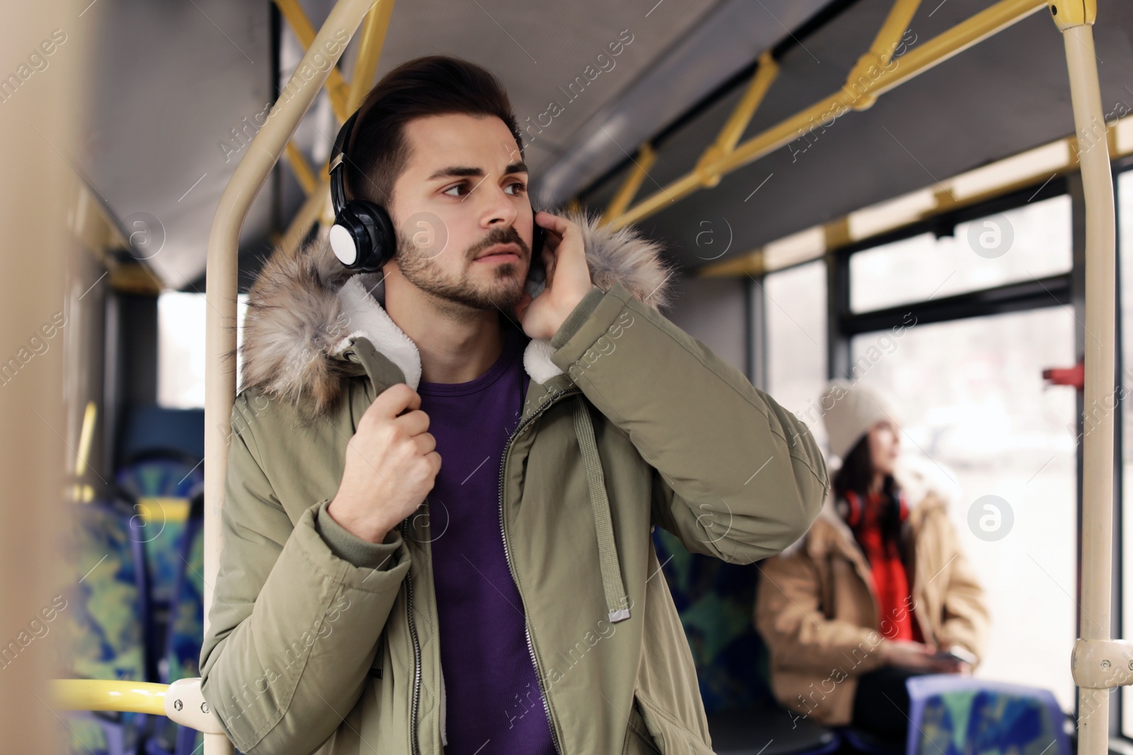 Photo of Young man listening to music with headphones in public transport