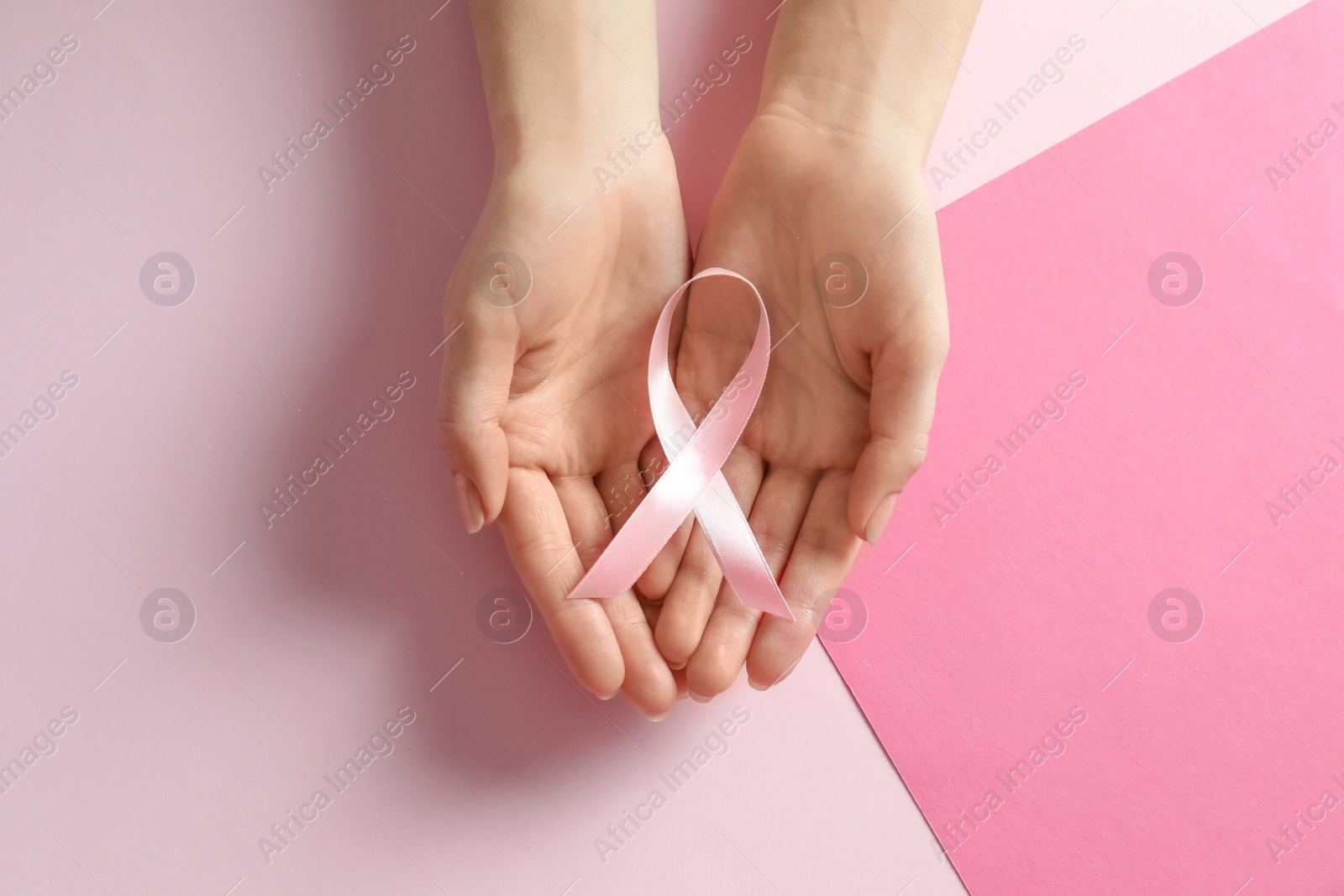 Photo of Woman holding pink ribbon on color background, top view. Breast cancer awareness