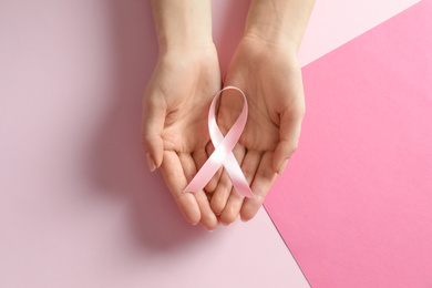 Woman holding pink ribbon on color background, top view. Breast cancer awareness