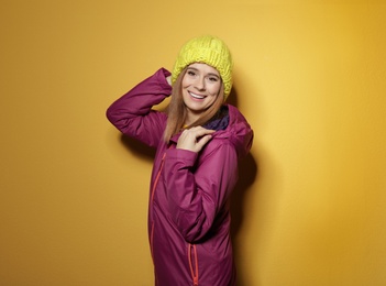 Young woman wearing warm clothes on color background, space for text. Ready for winter vacation
