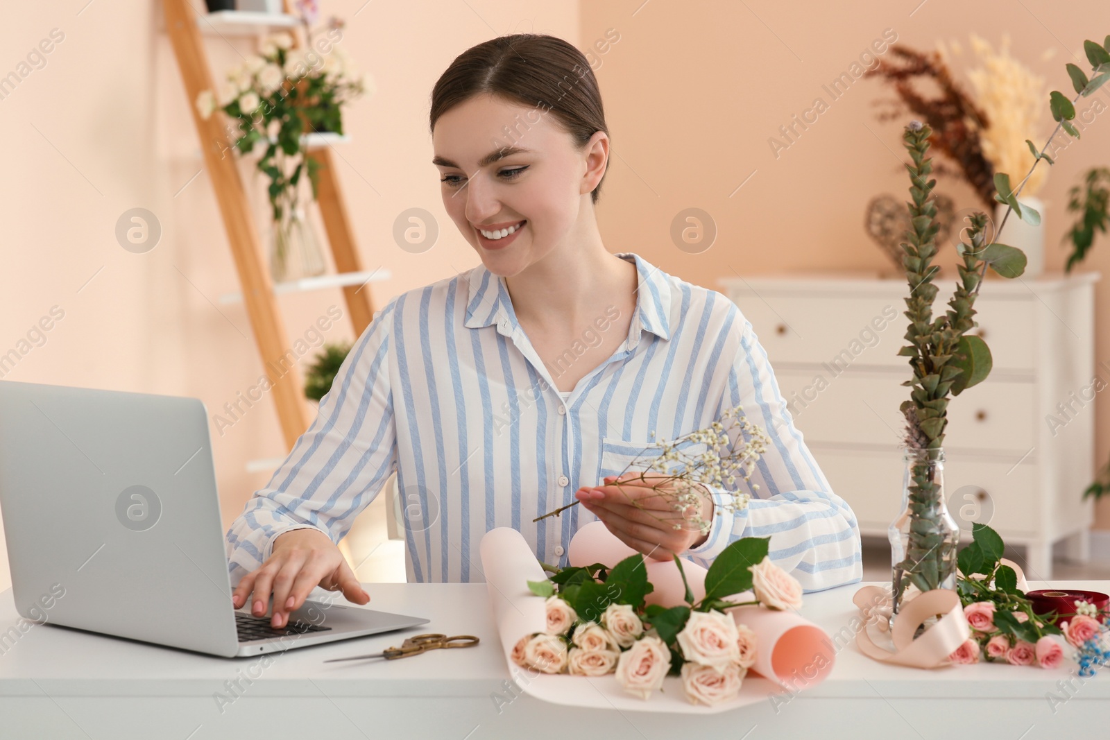 Photo of Woman making bouquet following online florist course at home. Time for hobby