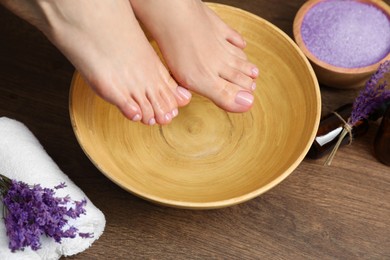 Photo of Woman soaking her feet in bowl with water, closeup. Pedicure procedure