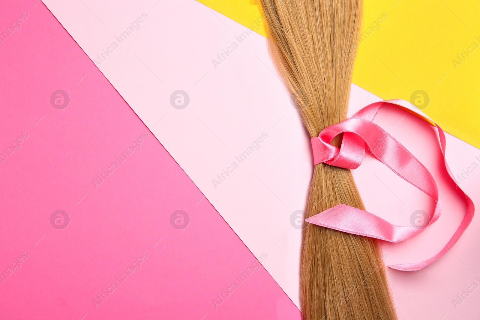 Photo of Blond hair tied with ribbon and space for text on color background, top view