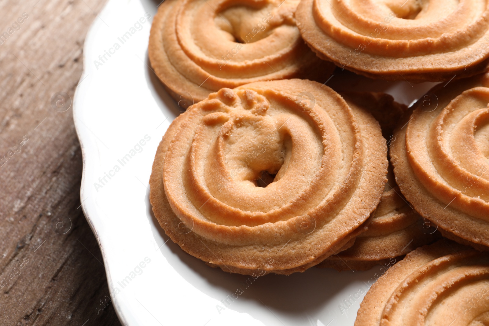 Photo of Plate with Danish butter cookies on wooden table, closeup