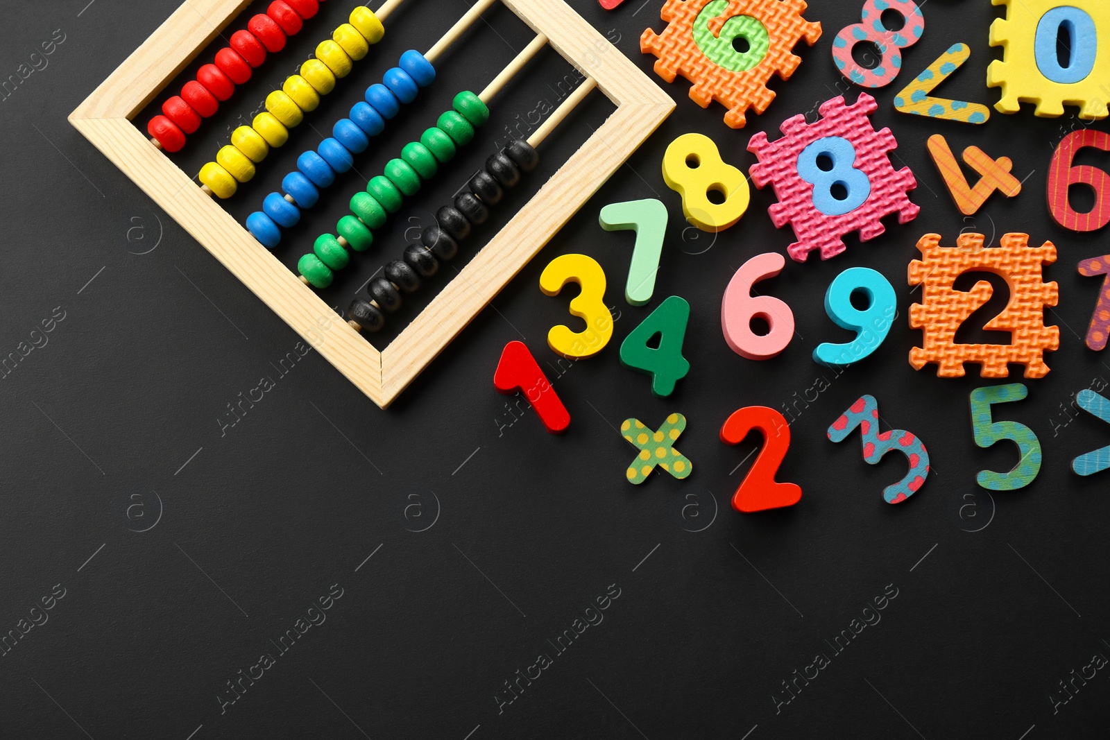 Photo of Many colorful numbers and mathematical symbols near abacus on black background, flat lay. Space for text