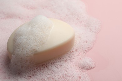 Soap with fluffy foam on pink background, closeup. Space for text