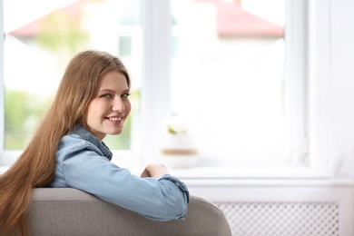 Photo of Young beautiful woman sitting near window at home