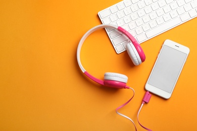 Photo of Modern headphones, phone and keyboard on color background, flat lay. Space for text