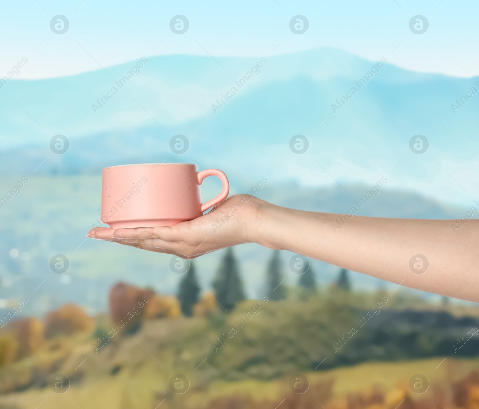 Image of Closeness to nature. Woman holding cup in mountains, closeup