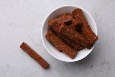 Photo of Crispy rusks with bowl on light table, flat lay