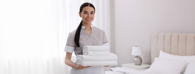 Image of Chambermaid with stack of fresh towels in hotel room. Banner design