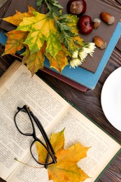 Photo of Maple leaves, book and glasses on wooden table, flat lay. Autumn atmosphere