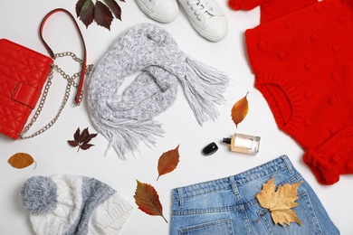 Photo of Stylish outfit and autumn leaves on white background, top view. Trendy warm clothes