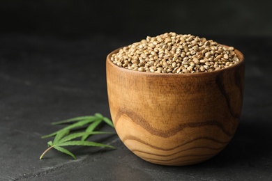 Photo of Organic hemp seeds in bowl on dark table