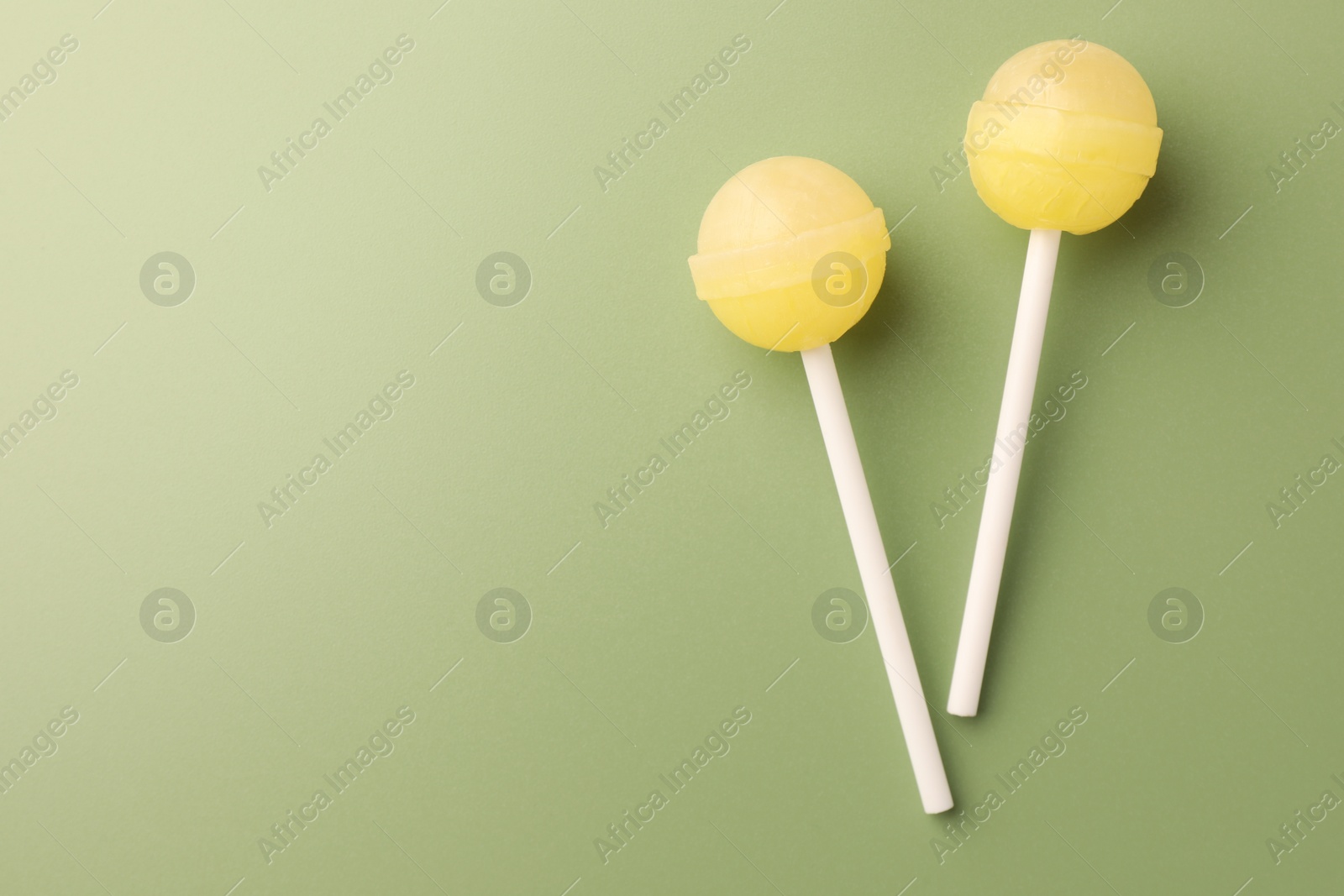 Photo of Tasty lollipops on green background, flat lay. Space for text