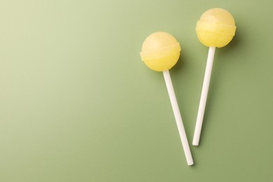 Tasty lollipops on green background, flat lay. Space for text