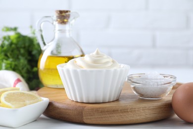 Photo of Fresh mayonnaise sauce in bowl and ingredients on table