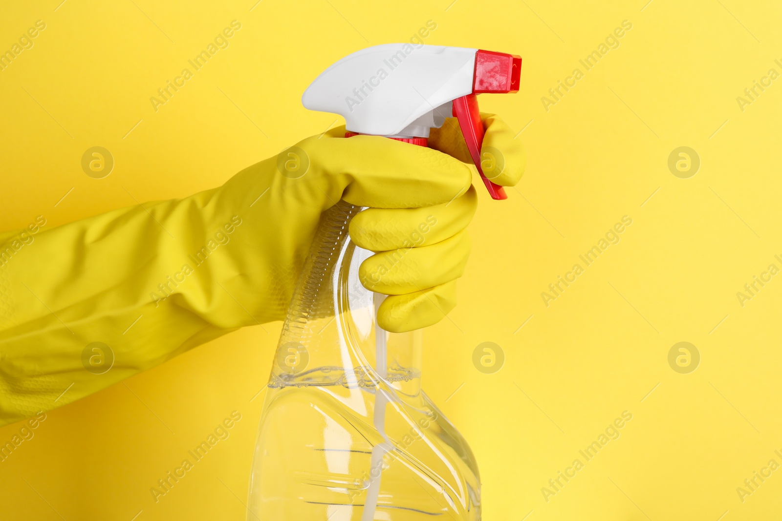 Photo of Woman holding plastic spray bottle on yellow background, closeup. Space for text