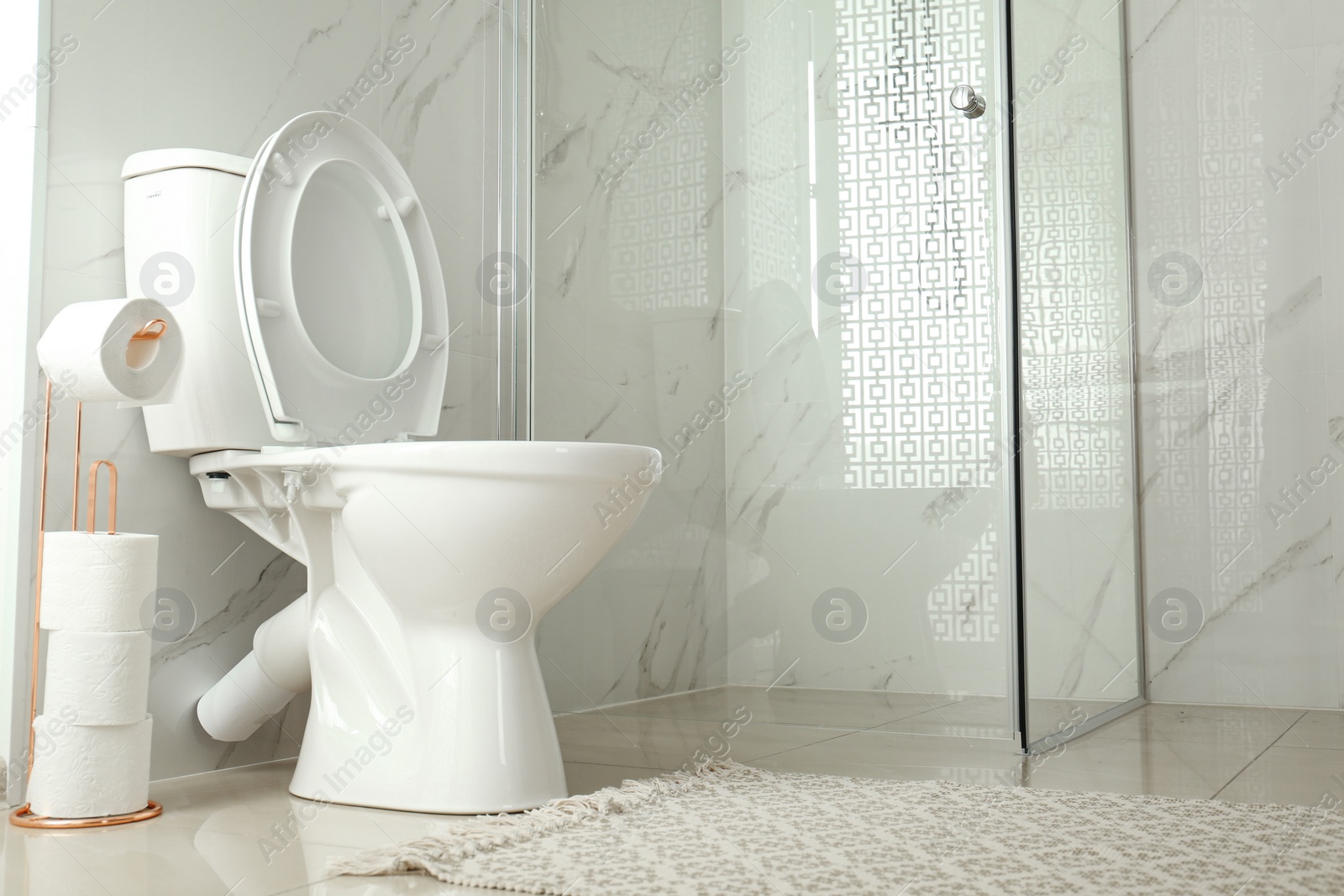 Photo of Toilet bowl near shower stall in modern bathroom interior