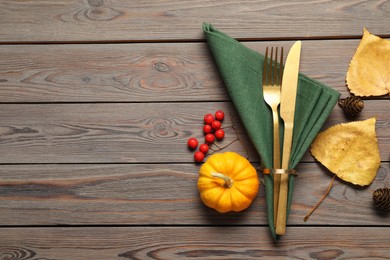 Photo of Napkin, cutlery, pumpkin and berries on wooden background, flat lay with space for text. Stylish autumn table setting