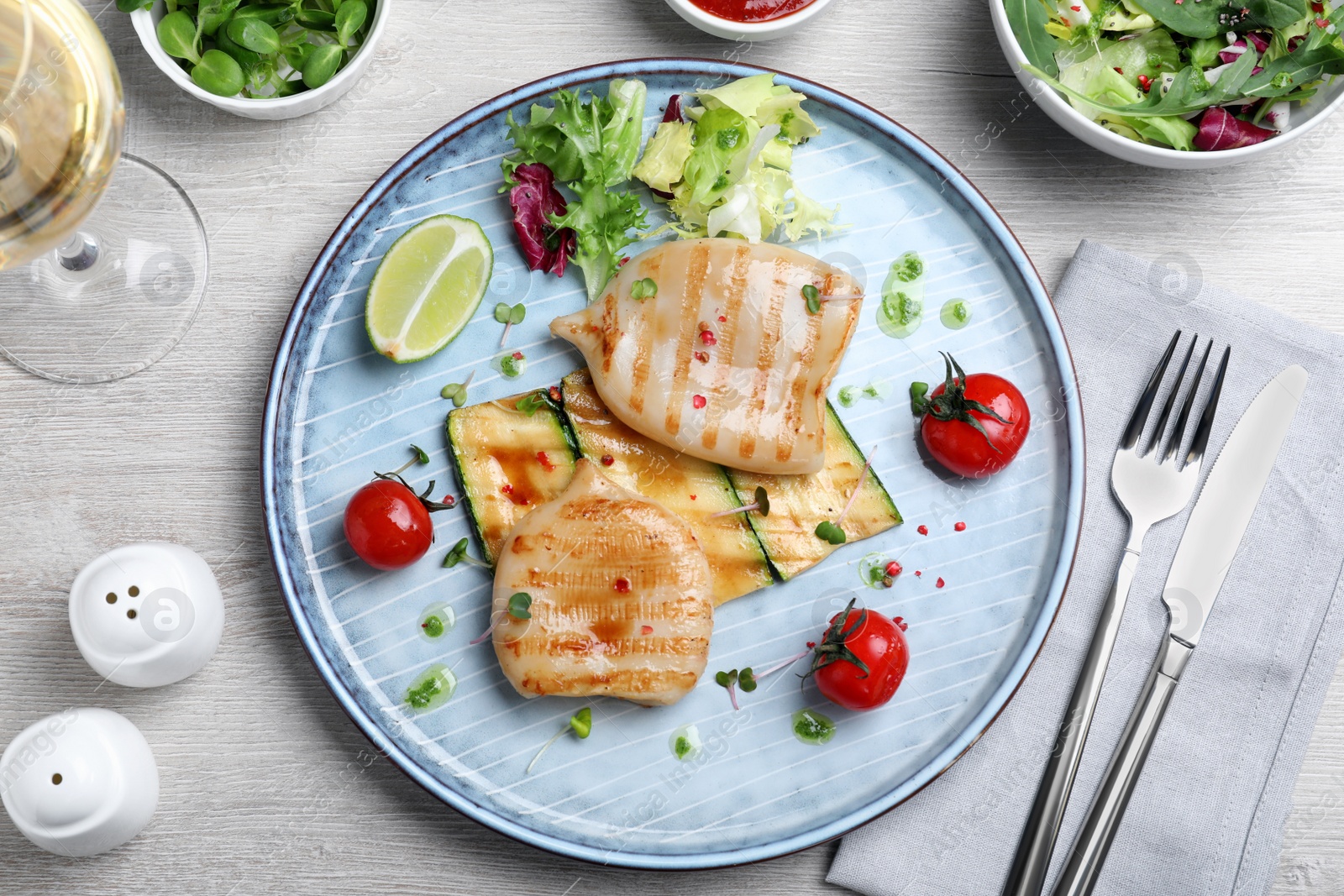 Photo of Grilled squid tubes served on white wooden table, flat lay