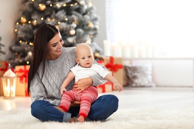 Photo of Mother with her cute baby at home, space for text. Christmas celebration