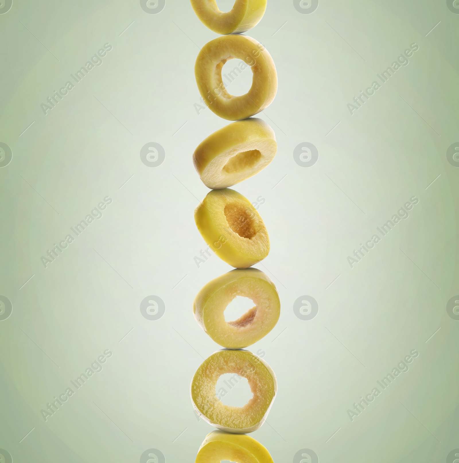 Image of Stacked slices of olive on pastel green gradient background