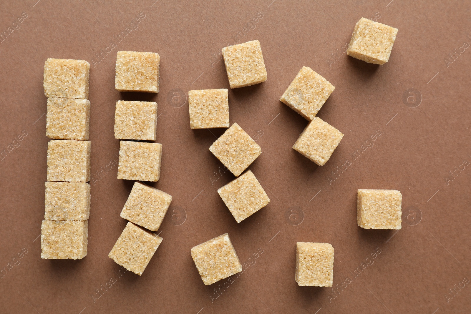 Photo of Brown sugar cubes on color background, top view